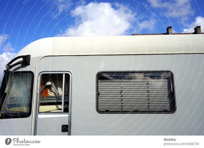 Modern large luxury-class motorhome packed to the top with high roof and blinds In light gray in a yard in an industrial park in Detmold in East Westphalia-Lippe in the sunshine