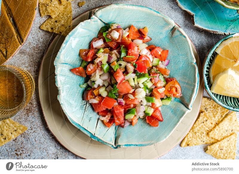 Fresh homemade pico de gallo salsa served with corn chips mexican tomato onion cilantro green bell pepper avocado lemon juice ceramic plate from above fresh