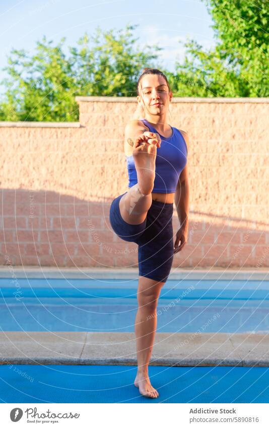 Woman practicing yoga by the pool in a serene setting woman fitness health wellness exercise tranquility serenity sunset outdoor balance stretching calm focused