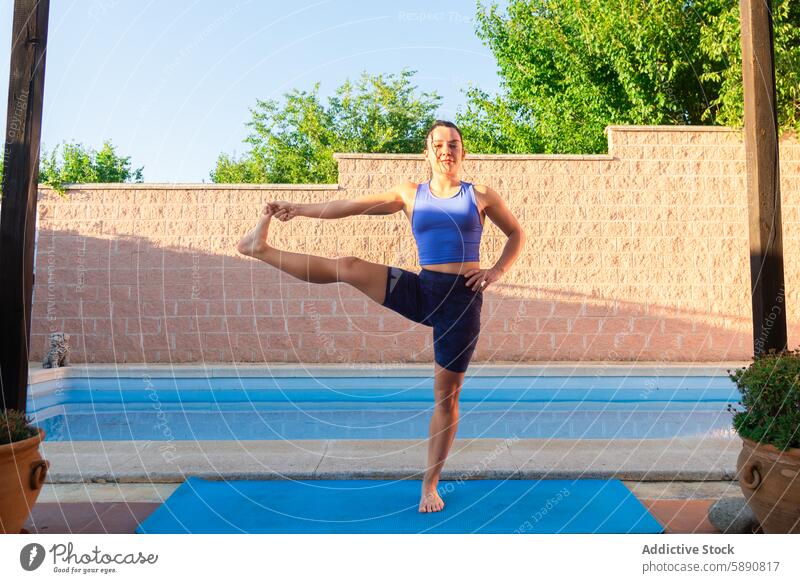 Woman practicing yoga by the poolside in daylight woman balance fitness health outdoor exercise tranquility peace relaxation wellness lifestyle healthy female