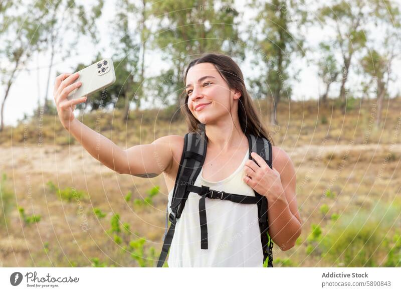 Young woman taking a selfie while hiking in nature hiker smartphone outdoor adventure smiling landscape young female technology backpack sport leisure travel