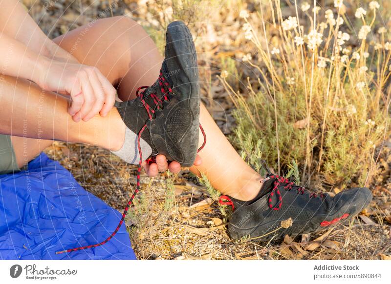 Hiker adjusting shoes on a countryside trail hiker adjustment trekking sleeping bag nature outdoor adventure leisure activity fitness health recreation foot