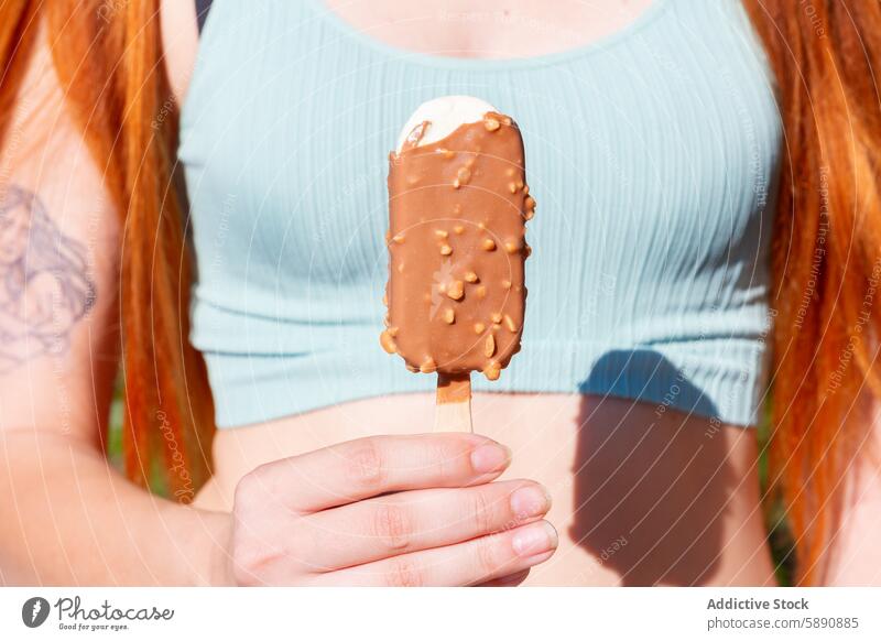 Summer indulgence with a chocolate ice cream bar summer woman treat sunny day dessert hand hold snack outdoor leisure season enjoyment sweet tasty frozen