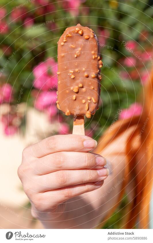 Enjoying chocolate and almond covered ice cream on a sunny day summer lifestyle nut hand dessert treat snack cold sweet indulgence freshness outdoor flower pink