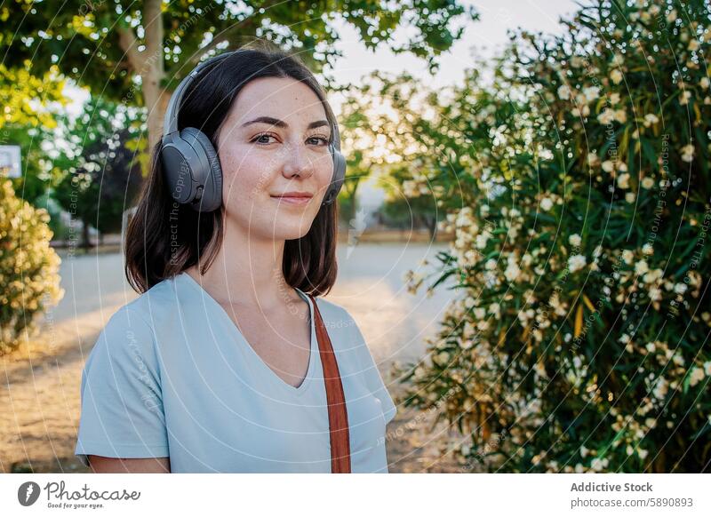 Young woman enjoying music with headphones in a park greenery flowers peaceful young adult female leisure enjoyment listening freckles gadget device nature