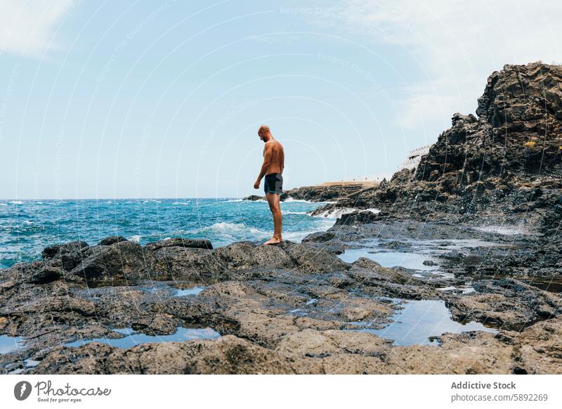 Man exploring rocky coastline on a sunny day man ocean sea wave nature shoreline summer holiday barefoot exploration adventure aquatic landscape serene outdoor