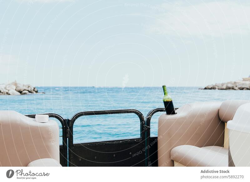 Relaxing boat scene with a bottle of wine on the sea ocean summer holiday coastline rock water sky clear railing serene calm relaxing luxury leisure beverage