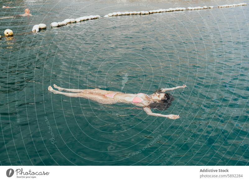 Woman enjoying a peaceful swim in calm sea waters summer holiday woman relaxation floating back sky clear blue tranquil leisure vacation travel outdoors nature