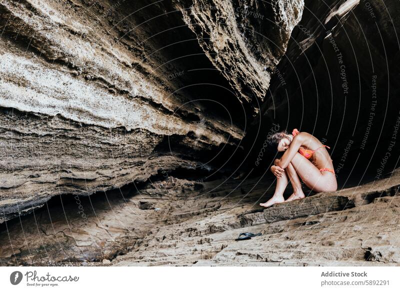 Young woman relaxing in a secluded rocky cave solitude peace summer holiday isolation nature bikini relaxation tranquility young female texture natural light