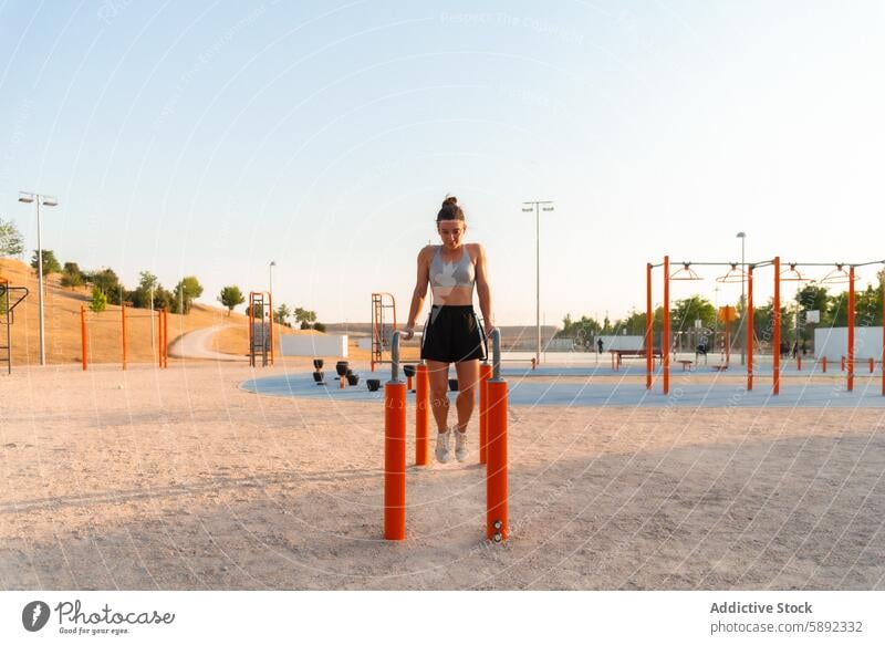 Young woman exercising at an outdoor park gym exercise street fitness routine athletic wear parallel bar urban environment daylight young public health wellness