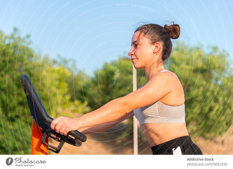 Young woman working out at an outdoor gym in summer exercise fitness street sunny focus effort workout equipment health sport active lifestyle physical training