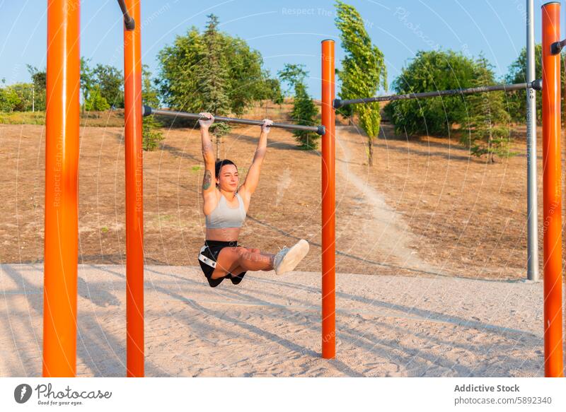 Young woman working out at outdoor gym in park exercise strength agility horizontal bar workout fitness health nature sport activity training strength training