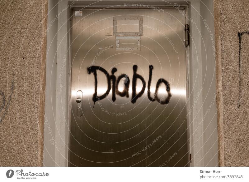 shiny metal door with the word Diablo spray-painted on it Metal door Glittering reflection splendour Spray Graffiti diablo Entrance Front door Closed