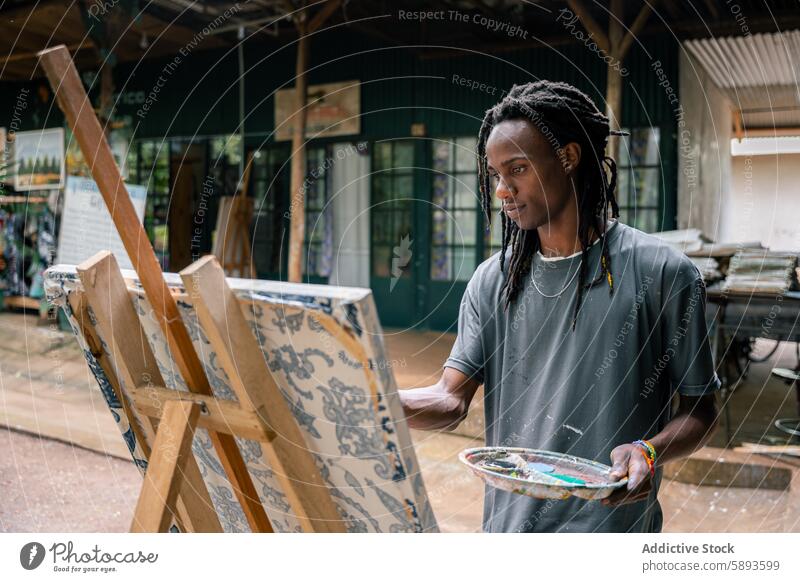 African american fine arts student paints in an outdoor classroom portrait african man african american stand young dreadlocks creativity canvas brush person