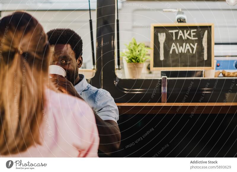 Black man drinking fresh beverage near woman outside food truck takeaway evening street rest couple to go relationship coffee cup tea girlfriend boyfriend