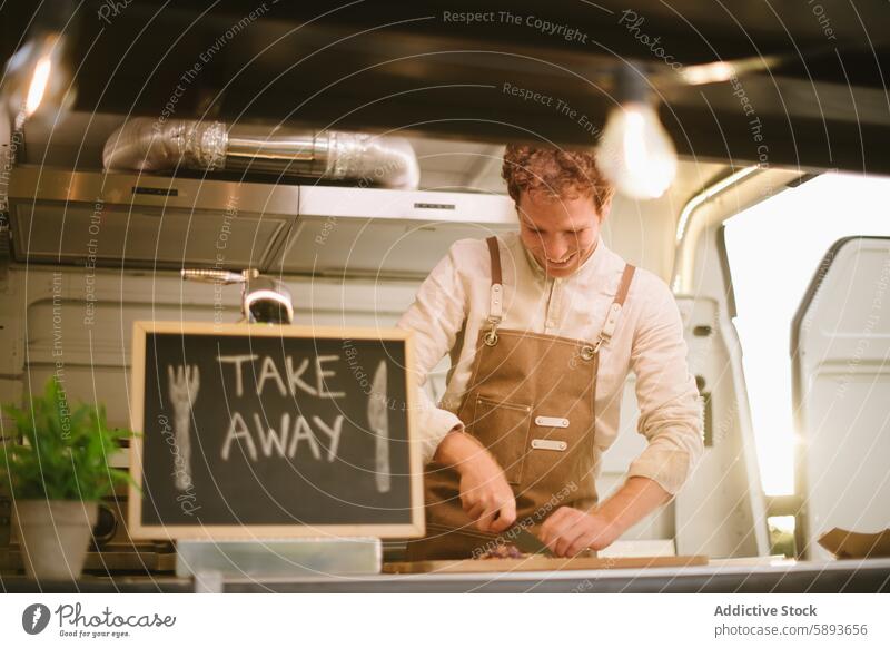 Happy cook cutting ingredients in food truck man chef work smile takeaway male happy chalkboard uniform apron small business owner blackboard glad staff