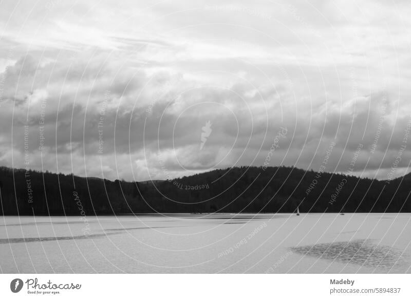 Approaching storm with threatening clouds over the mountains of the Kellerwald with sailing boats on the Edersee in the district of Waldeck-Frankenberg in Hesse in neo-realistic black and white