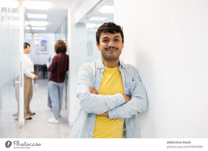 Smiling man and colleagues in modern English academy smile english academy hallway discussion young confident crossed arms education student tutor teacher