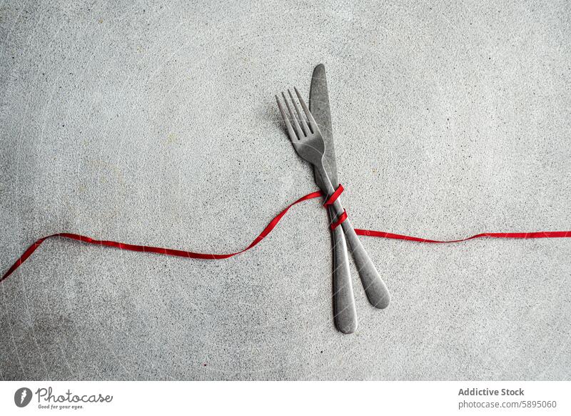 Minimalist table with a red ribbon on concrete background minimalist table setting knife fork texture simplicity style contemporary modern decor utensil