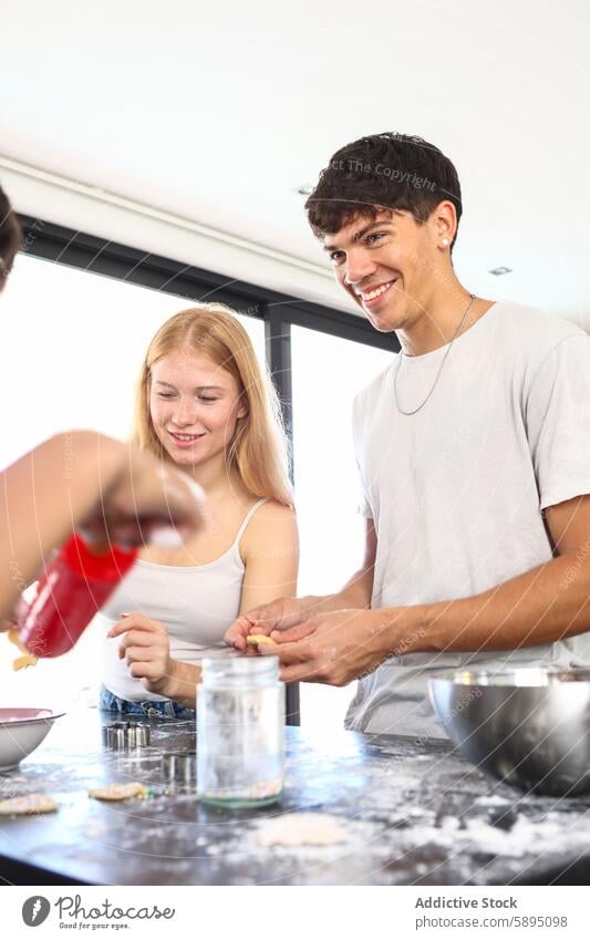 Siblings cooking together in a modern kitchen collaboration meal baking laughing joy sibling family casual indoor interaction home happiness flour bowl cookie