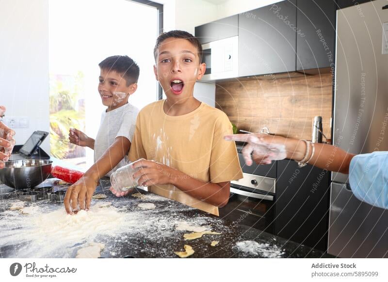 Siblings having fun while baking in the kitchen triplet brother cooking flour joy laughter playful culinary modern dough sibling male boy domestic activity bond