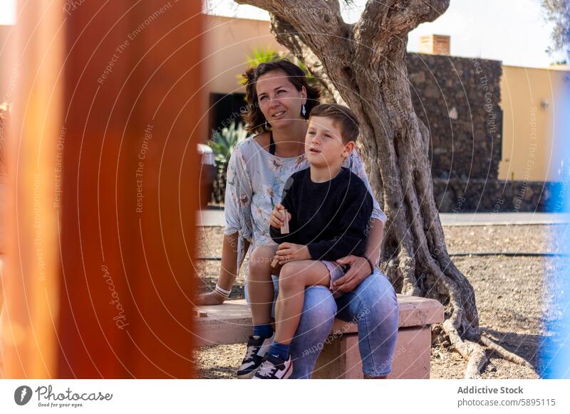 Mother and son sharing a moment on park bench mother family bonding outdoor seated woman boy looking at each other looking away thoughtful sunny afternoon