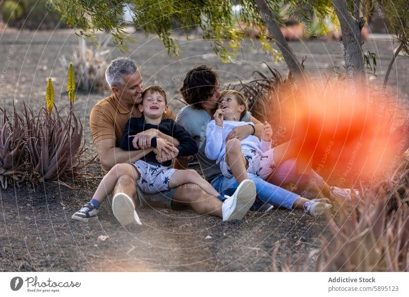 Family enjoying playful time together outdoors in autumn family park playing mother father sons trees affection smile bonding interaction casual happiness