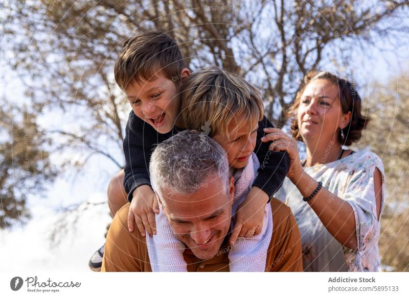 Family enjoying time together outdoors in autumn family park father mother sons boys siblings laughter nature interaction brother smiles engaging children