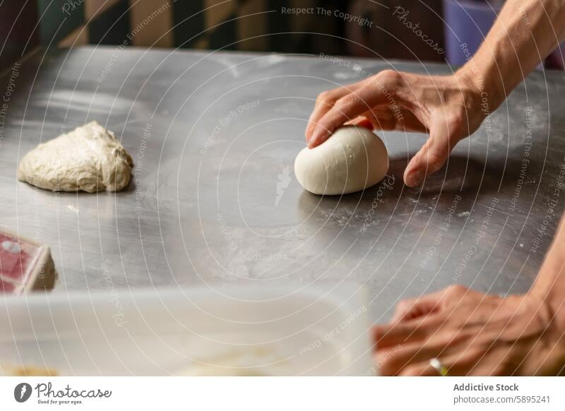 Close-up of hands kneading pizza dough on a table process kitchen metallic surface baking cooking food preparation detail close-up cuisine homemade artisan