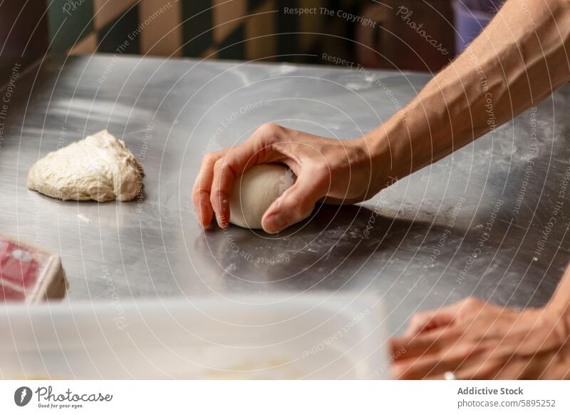 Hand kneading dough on a steel counter in a kitchen pizza hand chef preparation food cooking baking restaurant meal cuisine process homemade fresh work culinary