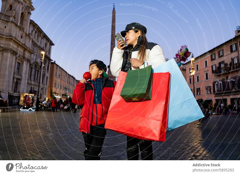 Asian family shopping at a Christmas market asian christmas mother son festive holiday winter candy apple outdoor evening bags phone technology communication