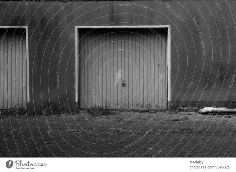 Old garage door of a garage in a washed-out facade in a backyard in the Pivitsheide district of Detmold in the Teutoburg Forest in East Westphalia-Lippe in classic black and white