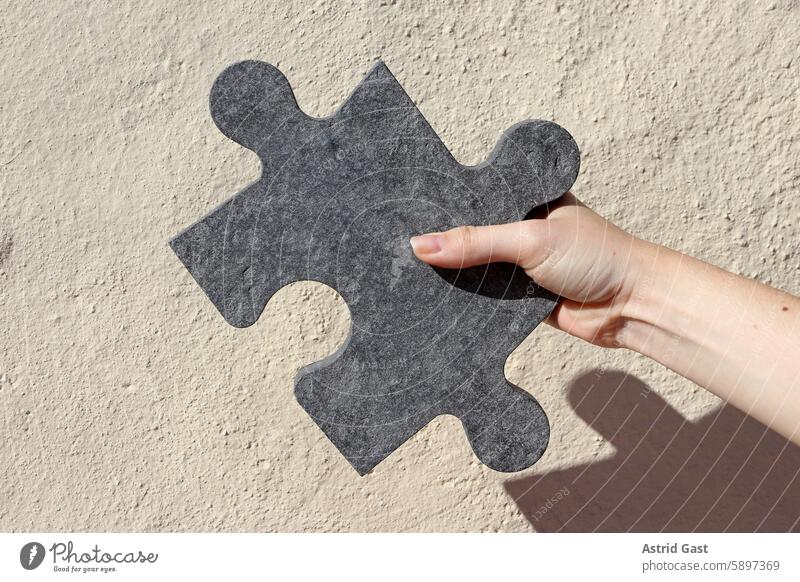 A woman holds a large stone puzzle piece in her hand Woman Hand Puzzle Puzzle piece portion jigsaw Stone Decoration stop Indicate Uphold game Toys Fingers motif