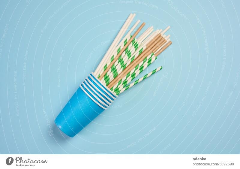 Paper cocktail straws and paper cups on a blue background, top view brown party recycling tube bar beverage biodegradable concept disposable drink eco ecology