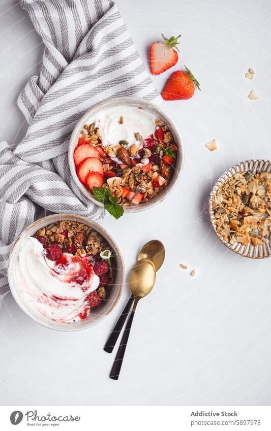 Top view of healthy granola bowls with yogurt and fruits breakfast strawberry summer nuts seeds food meal snack topping almond raspberry vegetarian nutrient