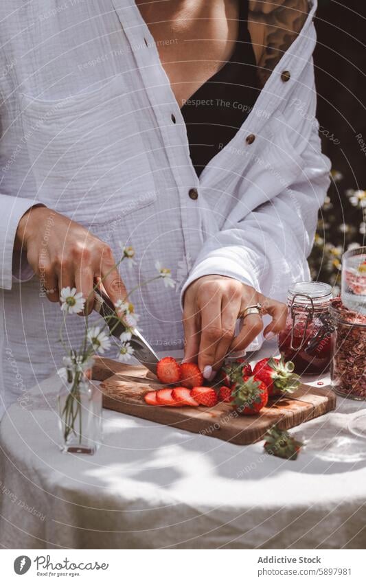 Preparing strawberries for a summer breakfast outdoors woman healthy strawberry slicing wooden board natural light flower unrecognizable anonymous faceless hand