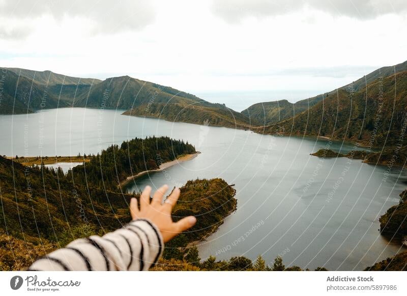 Hand pointing to a scenic view of Lagoa do Fogo, Sao Miguel, Azores. azores sao miguel lagoa do fogo landscape viewpoint water lake hills clouds sky nature