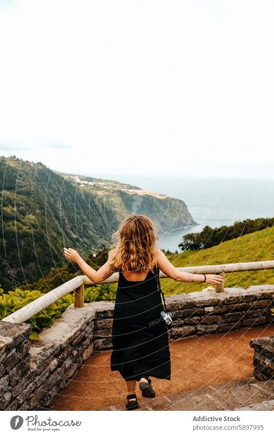Woman embracing scenic view from Sao Miguel, Azores. woman back view viewpoint sao miguel azores coastal cliff ocean arms spread outdoors nature travel tourism