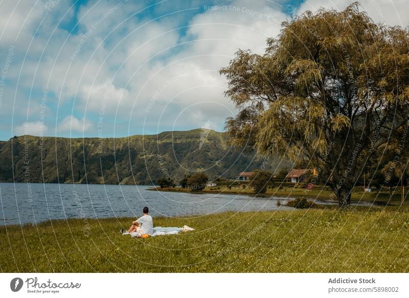 Man enjoys peaceful lakeside setting in Sao Miguel, Azores. man sao miguel azores tranquility serene lonely greenery hill nature male landscape outdoor grass