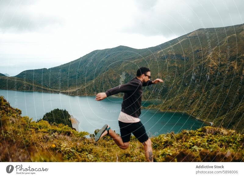 Man running outdoors overlooking a scenic lake in Sao Miguel. man sao miguel azores landscape green blue water nature hill movement fitness active adventure