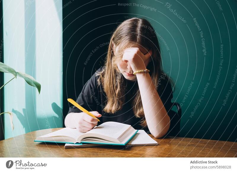 Young female student studying hard at a desk book education school young concentration focus tired learning stress sitting teenager youth academic anxiety pen