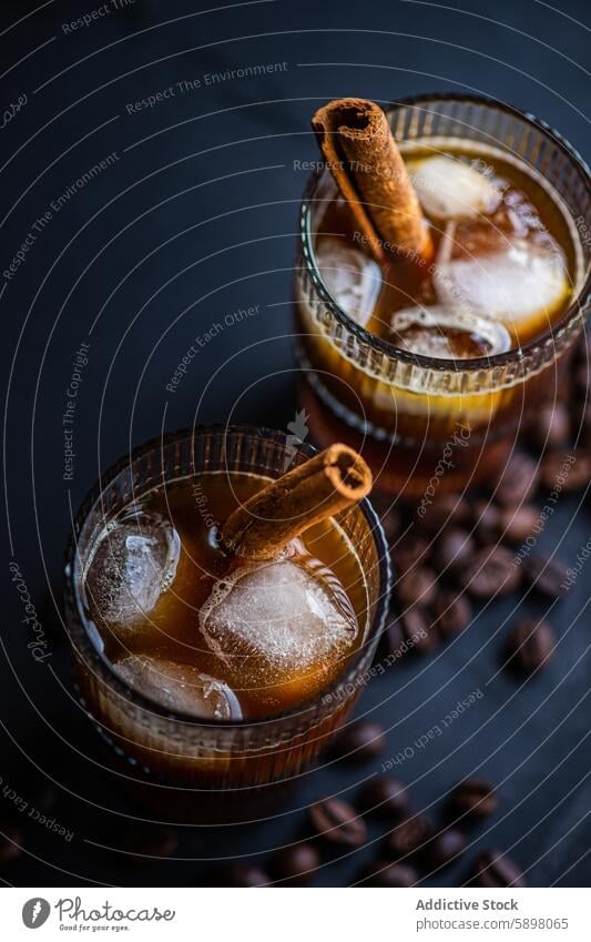 Close-up view of cold coffee drink garnished with cinnamon glass ice cube bean chilled beverage dark surface background aroma refreshment summer cafe style