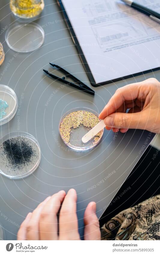 Female scientist hands taking sample of small plastic particles from glitter on petri dish in lab female micro microplastics nanoplastics microbeads laboratory