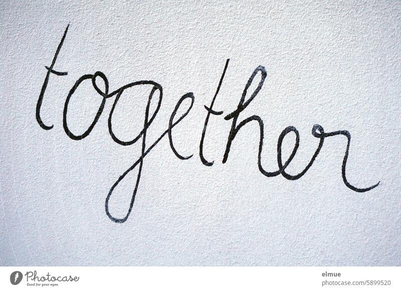 together is written in black cursive on a gray wall at the same time in common togetherness Simultaneous English lettering Blog Communication Opinion