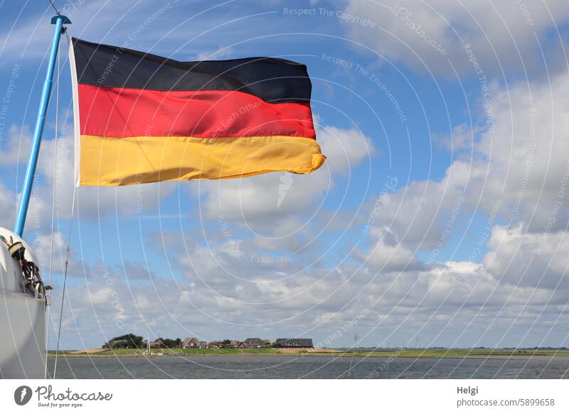 Waving German flag in front of a blue sky with clouds, Hallig Oland in the background Sky Clouds reverberant Holm Oland Ocean Water North Sea Nature Summer