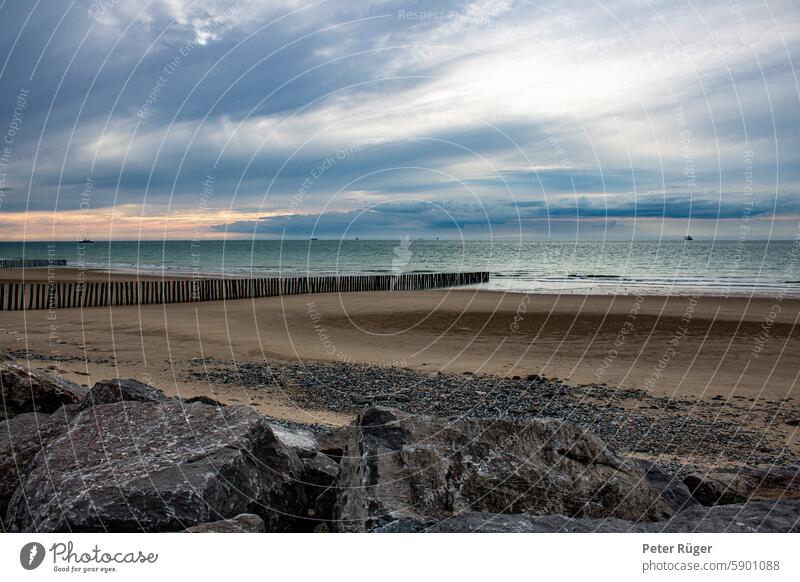 Sunset on an empty beach with breakwaters and rocks Beach North Sea Orange Red Yellow Gold Sky Blue Clouds Break water stakes Wood Green green Water Turquoise