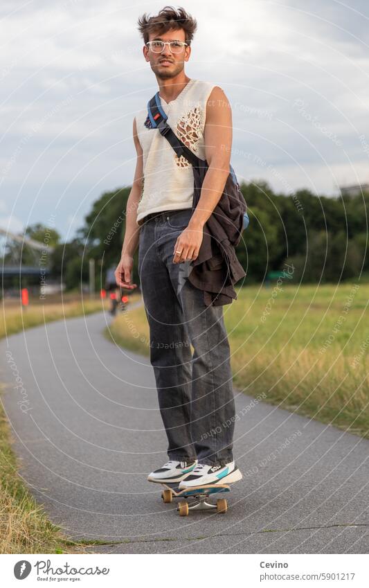 Young man from India rides a skateboard Man Athletic sexy Muscular kind Congenial Looking into the camera full of relish Exterior shot Nature Green erotic