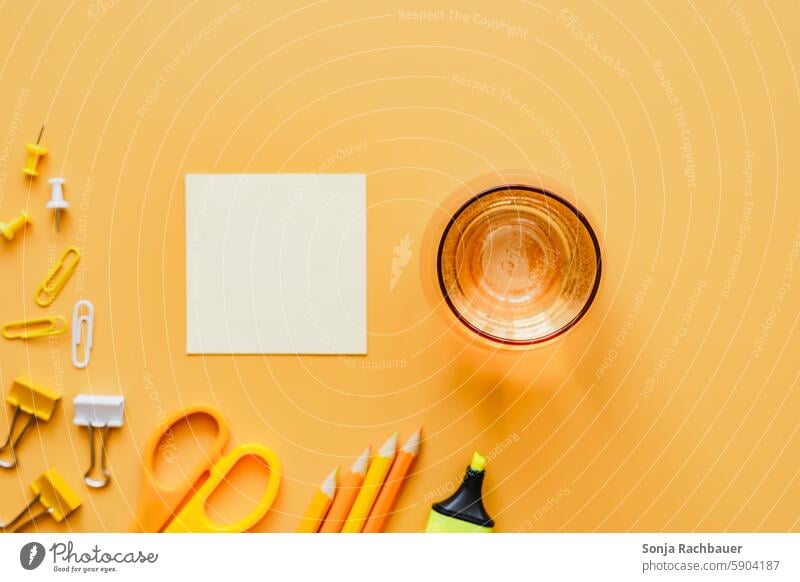 Office supplies, a blank notepad and a glass of water on an orange background. Top view. Tumbler Notepad Empty Cold drink Drinking water Fluid crayons