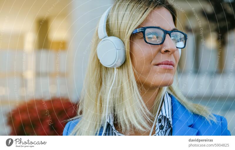 Businesswoman with nose piercing and headphones closeup businesswoman looking aside thoughtful street executive blazer young person caucasian lifestyle modern