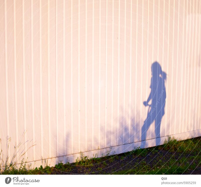 Shadow girl on a scooter Girl Child shadow figure children Playing fun Movement Driving Sun Summer Grass Scooter Vehicle Sports Wall (building) Stripe Braids